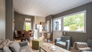 Un vaste espace de vie comprenant un canapé, des fauteuils, une table basse et un coin repas avec des chaises et une table.