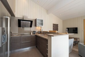 A modern kitchen with a central island, built-in appliances, and a flat-screen TV. - Mv Lodge (La Couarde-sur-Mer)