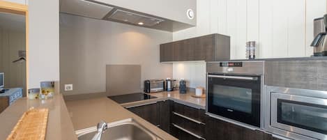A modern kitchen with dark cabinetry, stainless steel appliances, and a built-in oven.