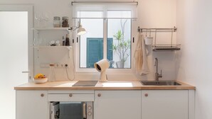 Eine moderne Küche mit weißen Schränken, einem eingebauten Backofen, einem Fenster mit blauen Rolläden und einer hängenden Stange.