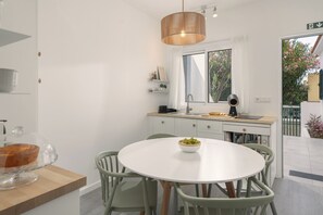 A modern kitchen with a round dining table, light green chairs, and a white countertop.