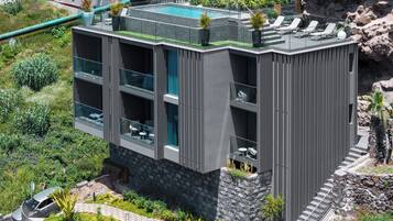 Un edificio moderno con piscina en la azotea, amplias ventanas y base de piedra.