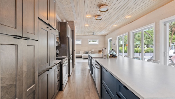 A modern kitchen with wooden cabinets, a large island, and a view of the outdoors.