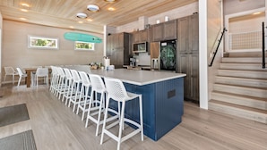 A modern kitchen with a central island, bar stools, and built-in appliances.