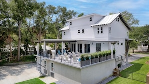 A two-story house with a covered patio, outdoor seating, and a staircase leading to a balcony.