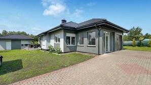 Ein modernes, zweistöckiges Haus mit Pflasterauffahrt und gepflegtem Rasen.
