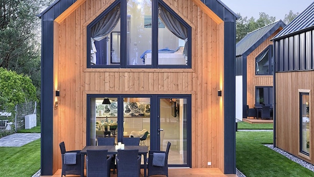 A modern two-story house with a wooden exterior, large glass windows, and a deck with outdoor furniture. - Lovely home in Bialogora with WiFi (Bialogora)