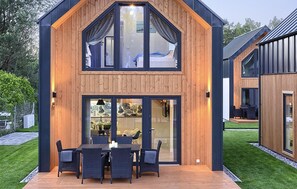 A modern two-story house with a wooden exterior, large glass windows, and a deck with outdoor furniture. - 2 bedroom luxurious home in Bialogora (Bialogora)