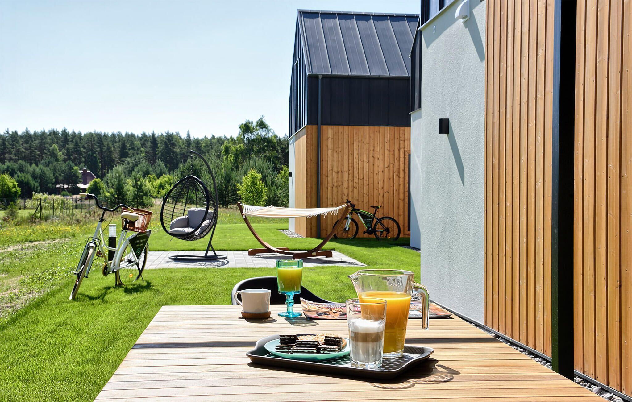 A wooden deck with a breakfast setup including a tray, glasses, and a bicycle.