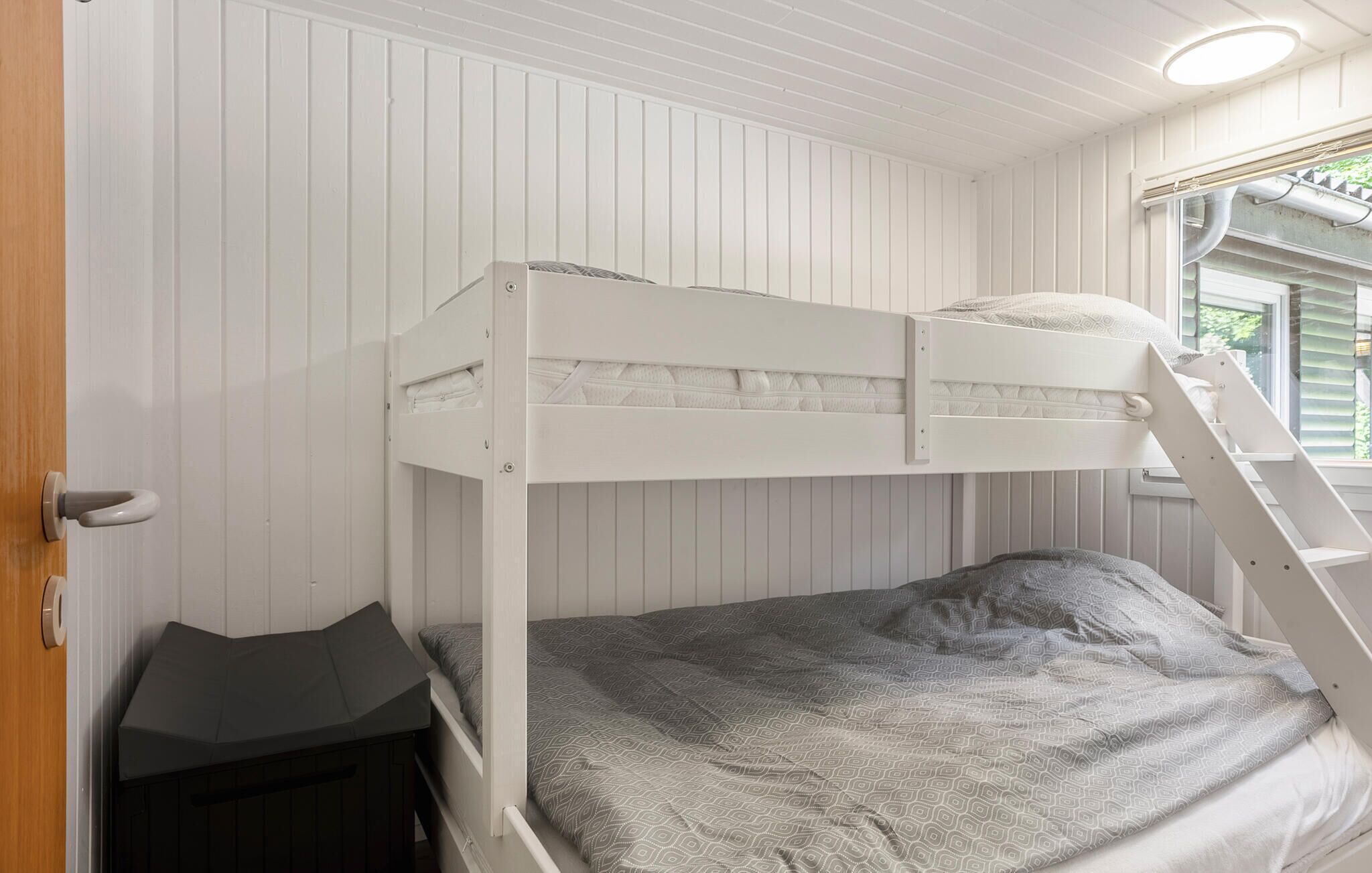 A bunk bed room with white walls and a window.