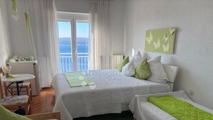 A hotel room with two beds, a small table, and a view of the sea. - Vila with 25 rooms (Dramalj)