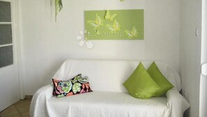 A white sofa with a colorful pillow and a green pillow, a wall with a green butterfly decoration, and a white wall hanging with the text "Dogma". - Vila with 25 rooms (Dramalj)