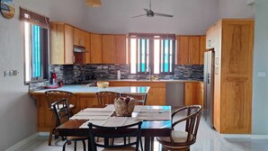 Una cocina moderna con armarios de madera, una isla central y un comedor con sillas.