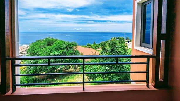 Un balcón con vistas al mar y al verdor.