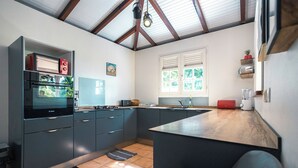 A modern kitchen with a built-in oven, a sink, and a window with blinds.