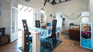 A dining area with a table set for four, a sofa, and a decorative shelf with a lamp.
