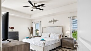 A bedroom with a bed, bedside tables, a TV, and a ceiling fan.