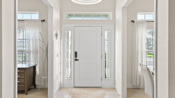 A hallway with a white door, a wooden desk, and a window with blinds.