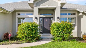 A two-story house with a dark front door, a small porch, and two side windows.