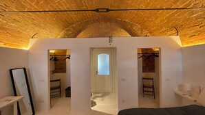 Une chambre avec un plafond en briques, un lit, un bureau et une armoire.