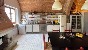 Une cuisine avec des meubles blancs, une table à manger noire et un plafond en briques.
