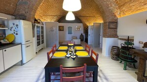 Une cuisine rustique avec un plafond en briques en forme d’arc, une table à manger avec des sets de table jaunes et des chaises en bois.
