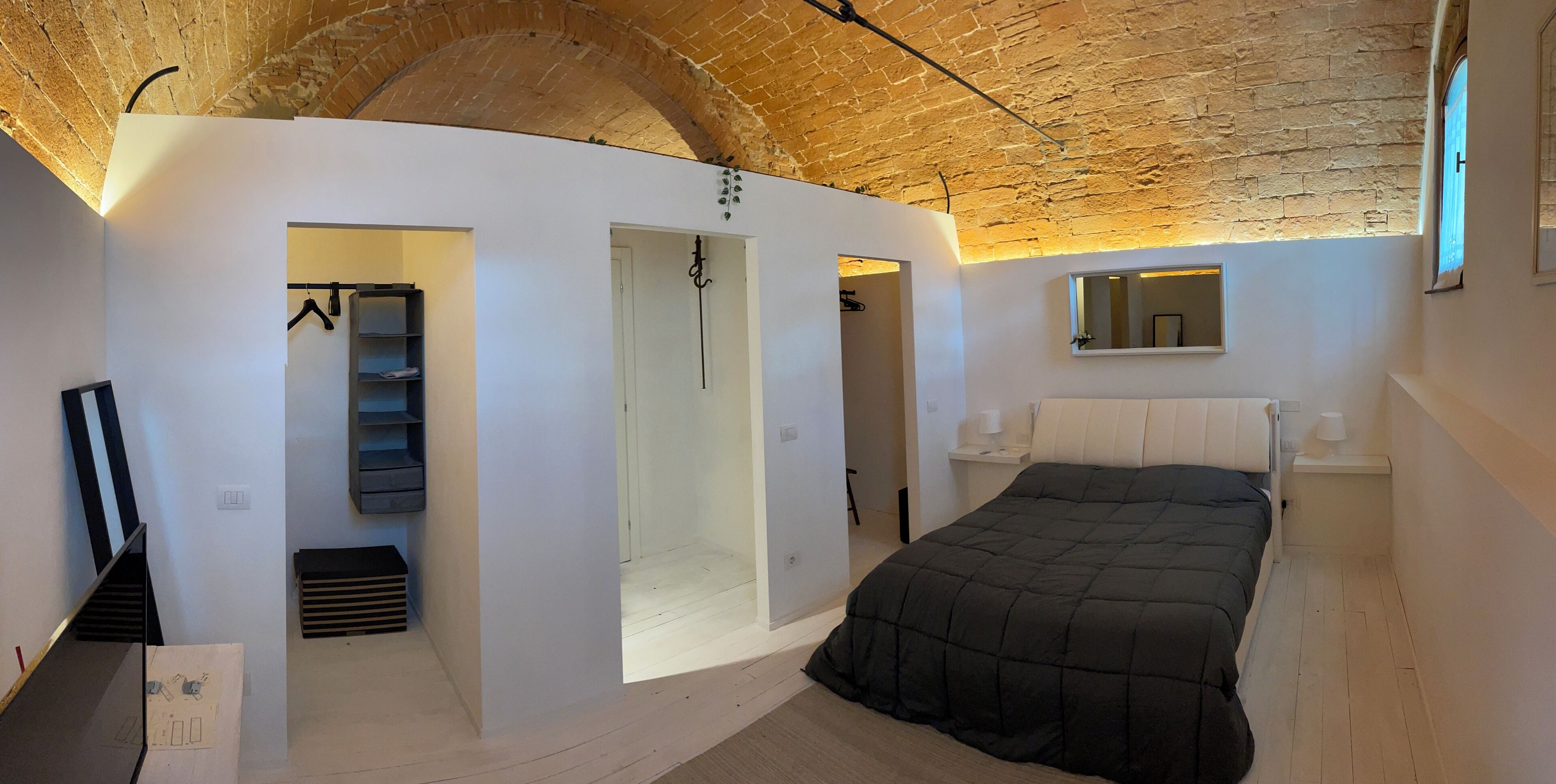 Ein Schlafzimmer mit einem großen Bett, einem Kleiderschrank, einem Spiegel und einer Treppe zu einer Schlafgalerie.