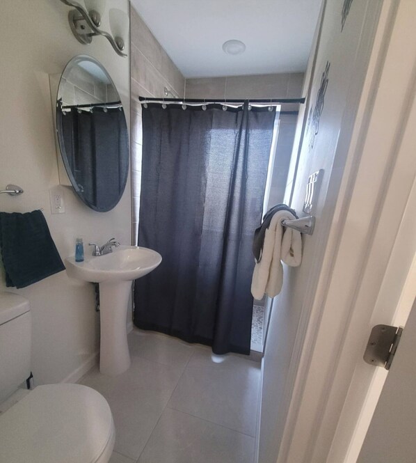 A bathroom with a toilet, sink, and shower curtain.