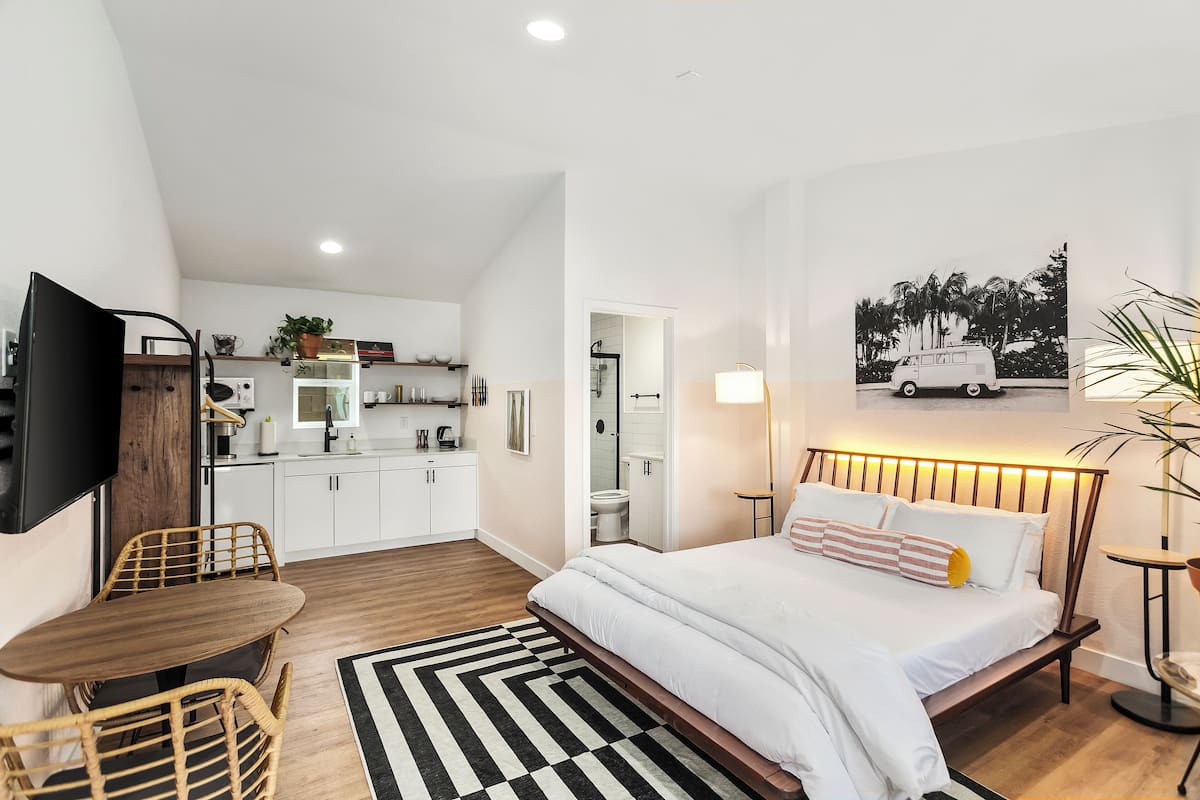 Una camera da letto moderna con un letto, un comodino e vista sulla cucina.