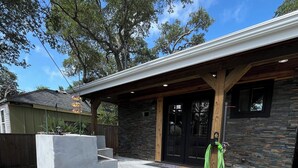 A modern building with a stone facade, a covered patio area, and a concrete seating arrangement.