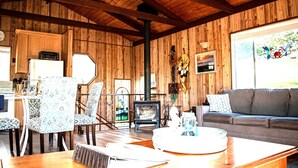 Un intérieur en bois comprenant un coin repas, un canapé, une cheminée et un espace cuisine.