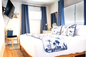 Une chambre à coucher comprenant un lit, une chaise, un bureau et un téléviseur fixé au mur.