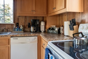 A kitchen with wooden cabinets, a coffee maker, a kettle, and a coffee bar sign.
