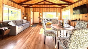 Un intérieur en bois comprenant un coin repas, un canapé et un téléviseur.