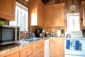 Una cocina con gabinetes de madera, microondas, cafetera y estufa.