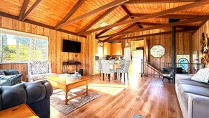 Un intérieur en bois comprenant un coin repas, des canapés, un téléviseur et une cheminée.