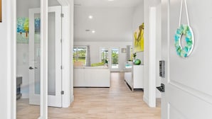 Un intérieur moderne avec un plancher en bois, des murs blancs et un espace cuisine doté d’un grand îlot central.