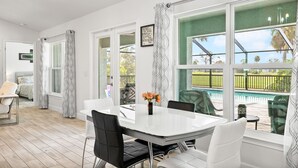 A spacious room with a large dining table, white chairs, and a view of a swimming pool. - Newley Built/Heated Pool/Golf Course Views/Sleeps 9 (Rotonda West)