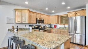 A kitchen with granite countertops, stainless steel appliances, wooden cabinets, and bar stools. - Deer Valley La Casa Boulder Creek (Park City)