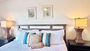 A neatly made bed with a patterned bedspread and multiple pillows, flanked by two bedside tables with lamps. - Private Beach Access, Steps from Ocean, Heated Pool, Garage, Beach towels/chairs (St. Augustine)