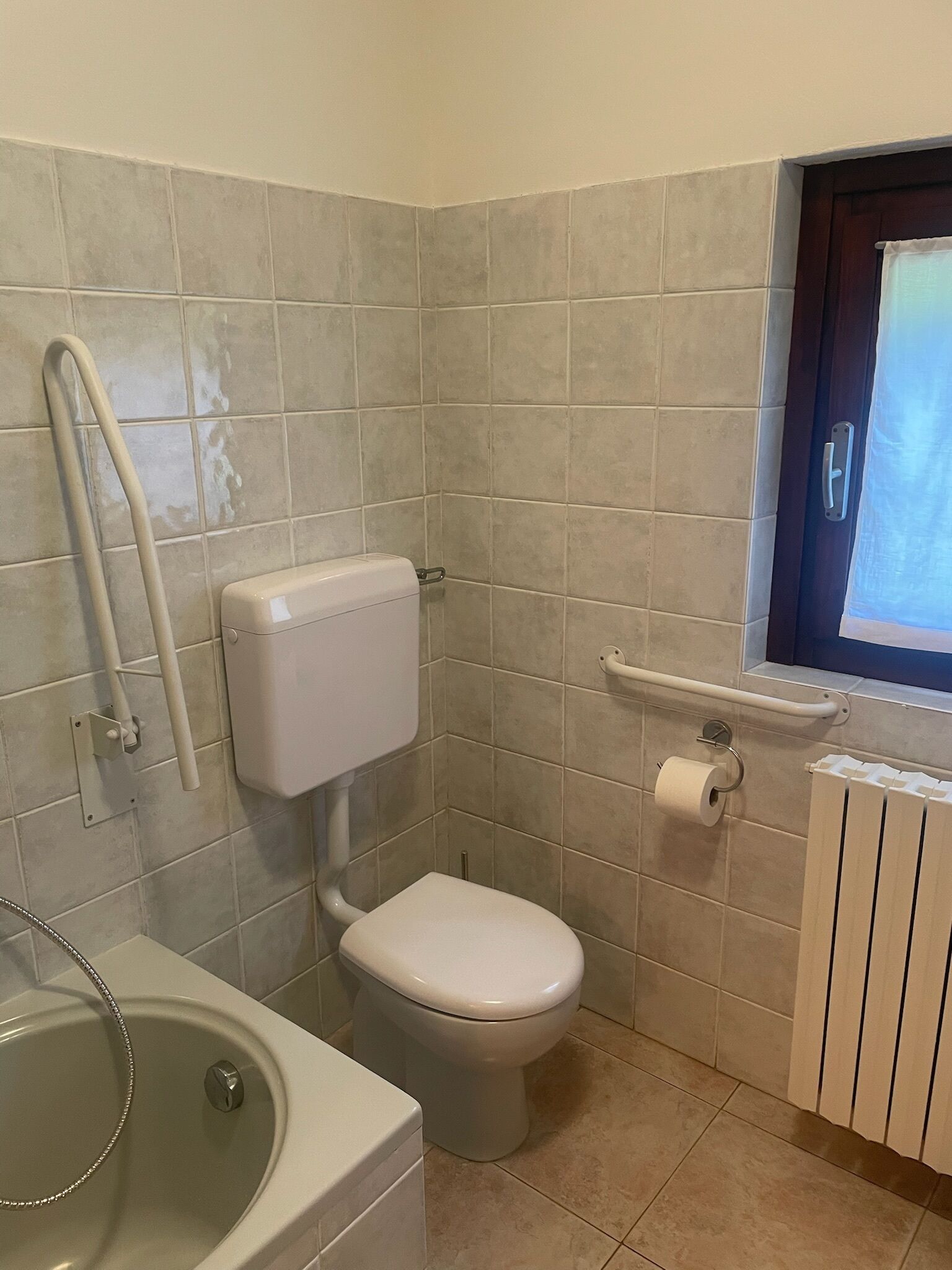 Un baño con inodoro, bañera y ventana.