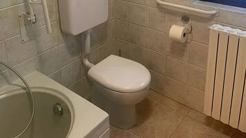 Un baño con inodoro, bañera y ventana.