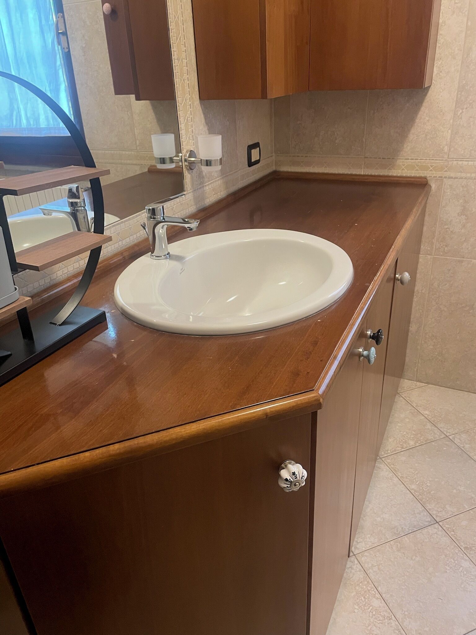 Ein Badezimmer mit Waschbecken, Holzschrank und Fliesenboden.