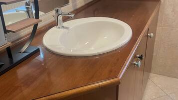 Ein Badezimmer mit Waschbecken, Holzschrank und Fliesenboden.
