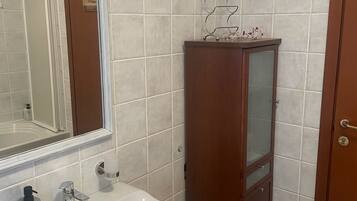 Un baño con un lavabo blanco, un mueble de madera y un espejo.