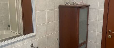 Un baño con un lavabo blanco, un mueble de madera y un espejo.