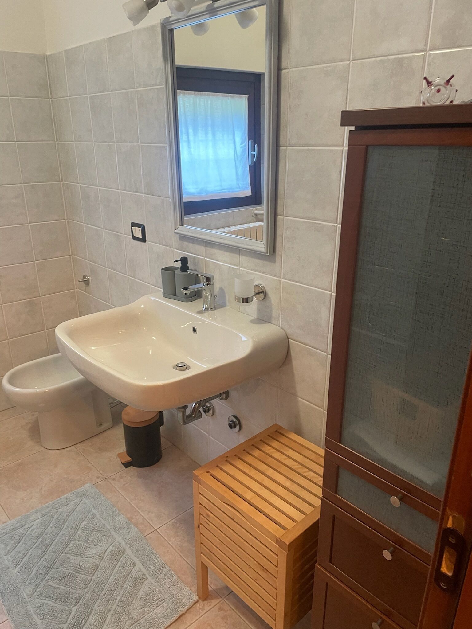 A bathroom with a sink, toilet, and mirror.
