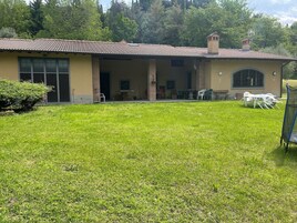 Una casa a due piani con tetto in tegole, veranda coperta e giardino con prato.