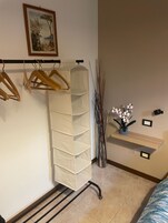 Una camera da letto ordinata con un letto, un armadio a muro, uno scaffale con oggetti decorativi e un quadro appeso al muro.
