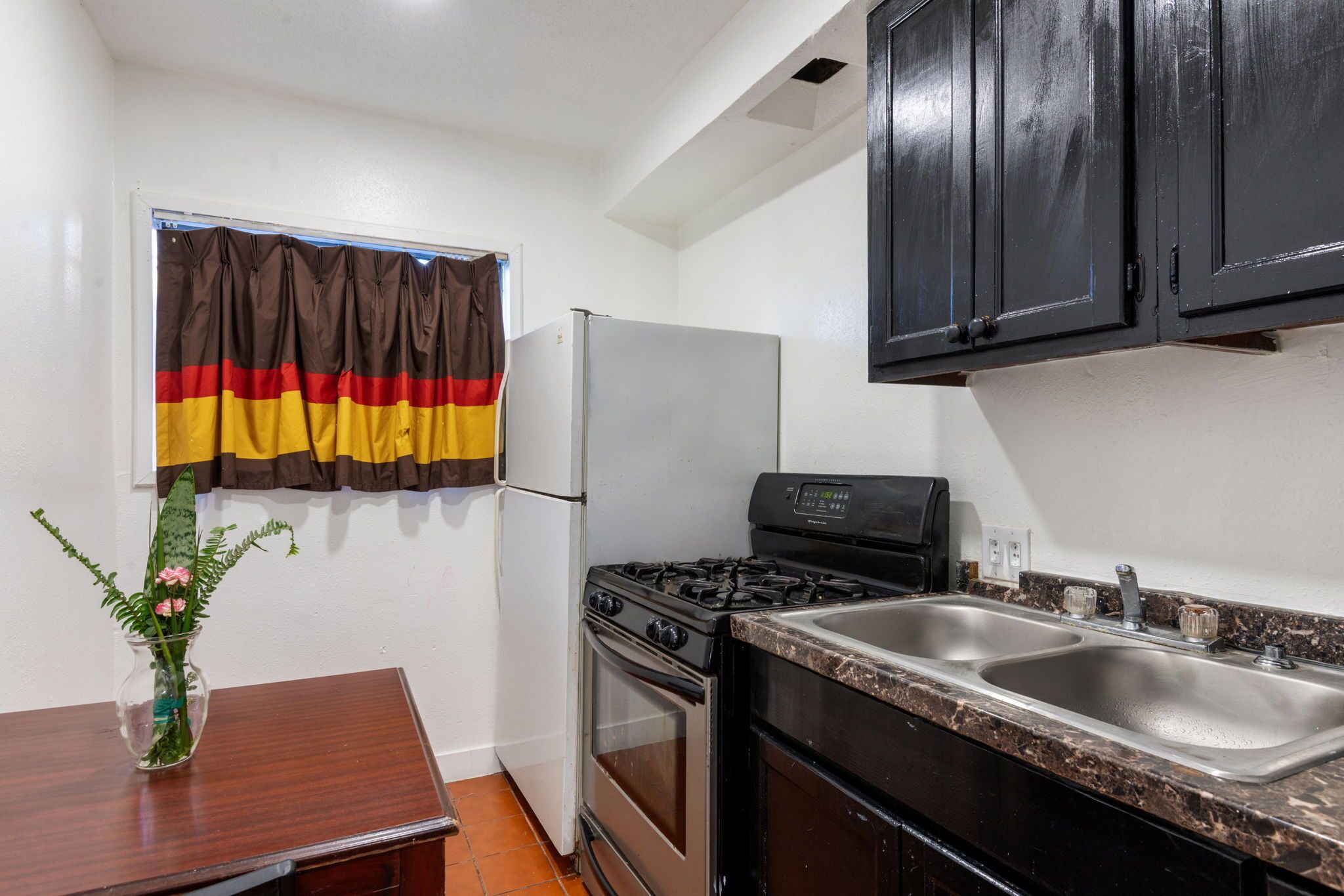 A compact kitchen with a refrigerator, stove, and sink.